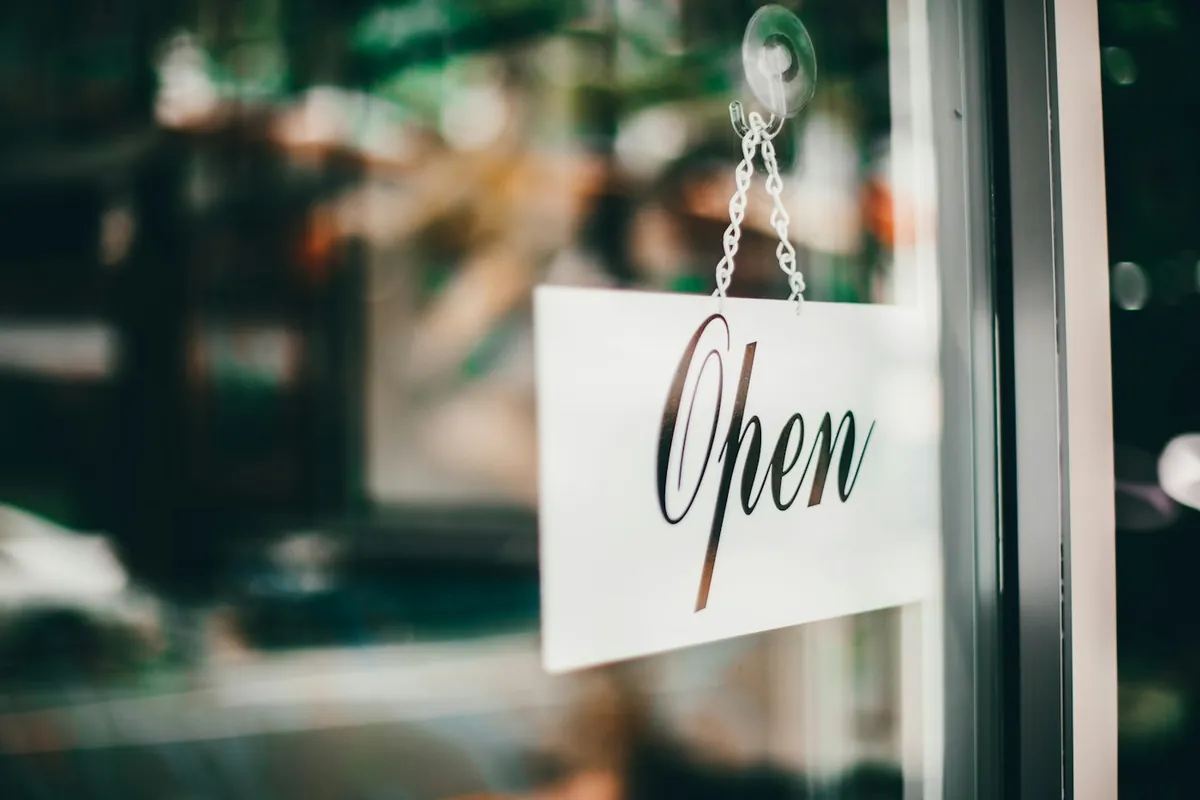 An Open sign hanging in the window of a local shop