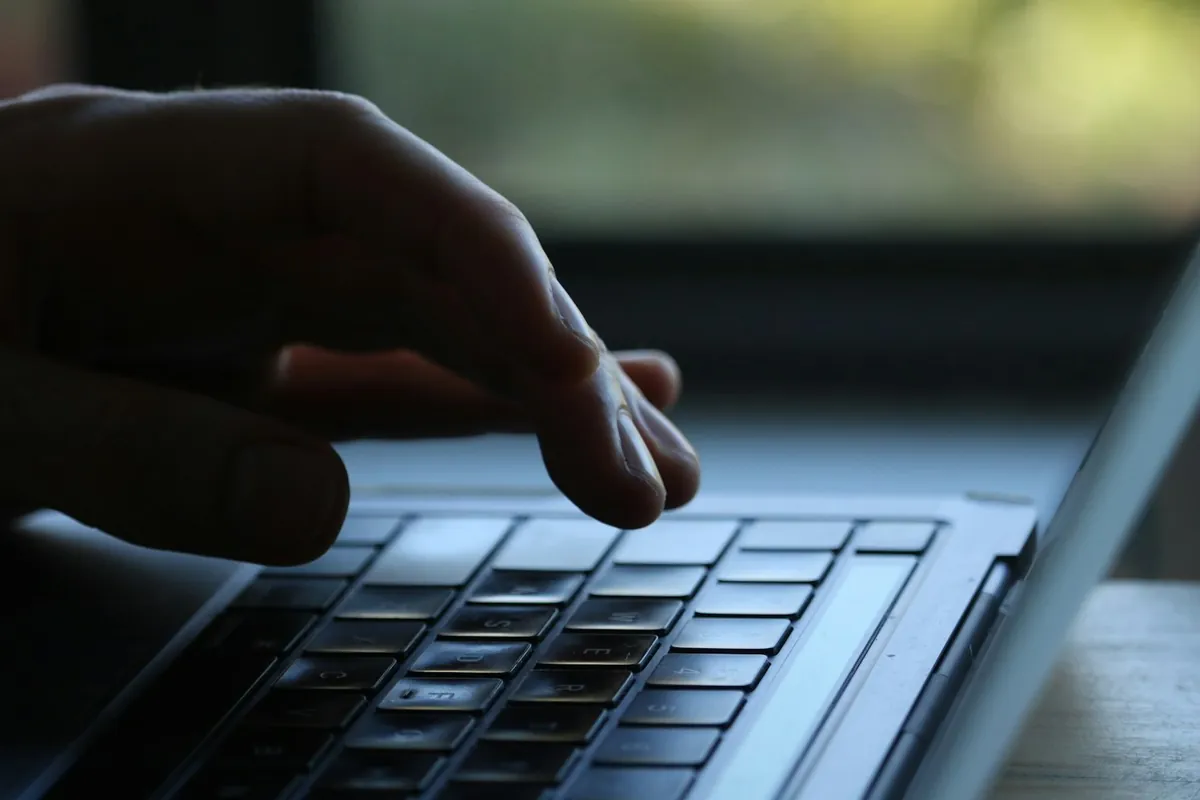 A hand resting on a laptop keyboard, the quiet upkeep a website care plan covers